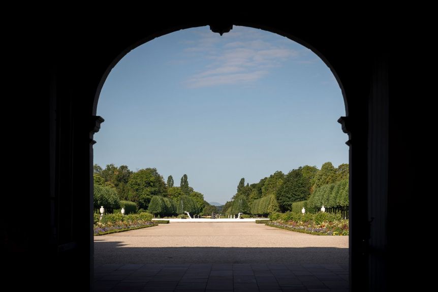 Blick durch das Tor von Schloss Schwetzingen in den symmetrisch angelegten Schlossgarten mit zentraler Allee.